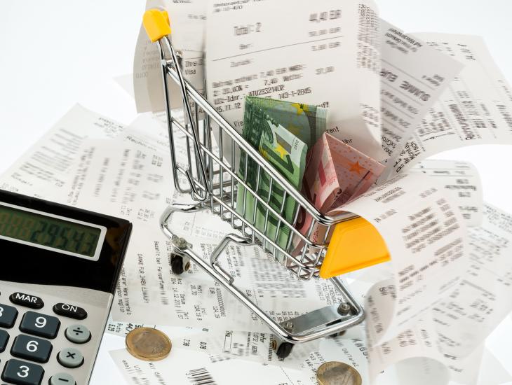 Een klein winkelwagentje is gevuld met kassabonnen en eurobiljetten.