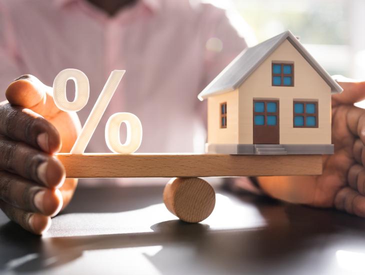 Een huisje en een procent-teken balanceren op een weegschaal