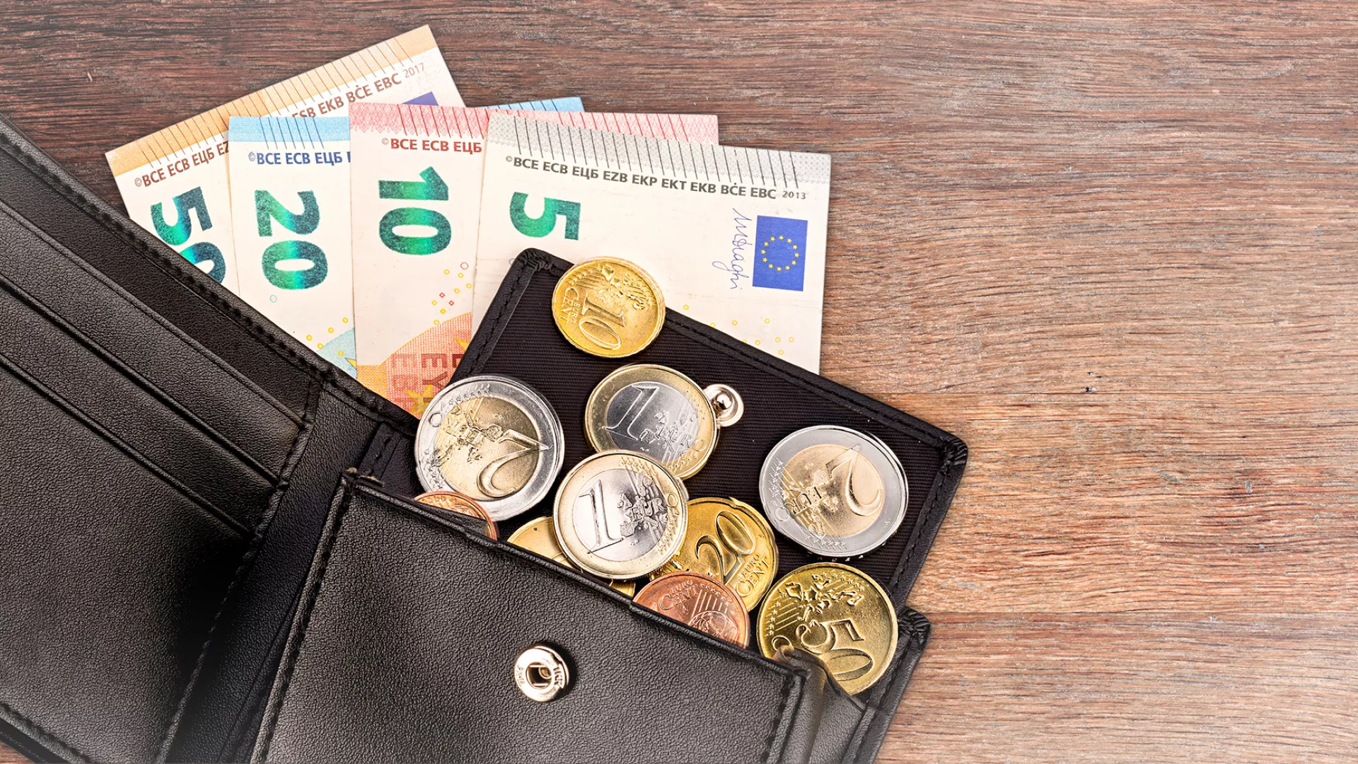 Een open portemonnee met briefgeld en losse euro's ligt op tafel