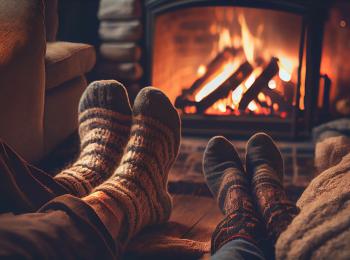 Een stel zit op de bank voor de open haard met hun voeten op de salontafel.